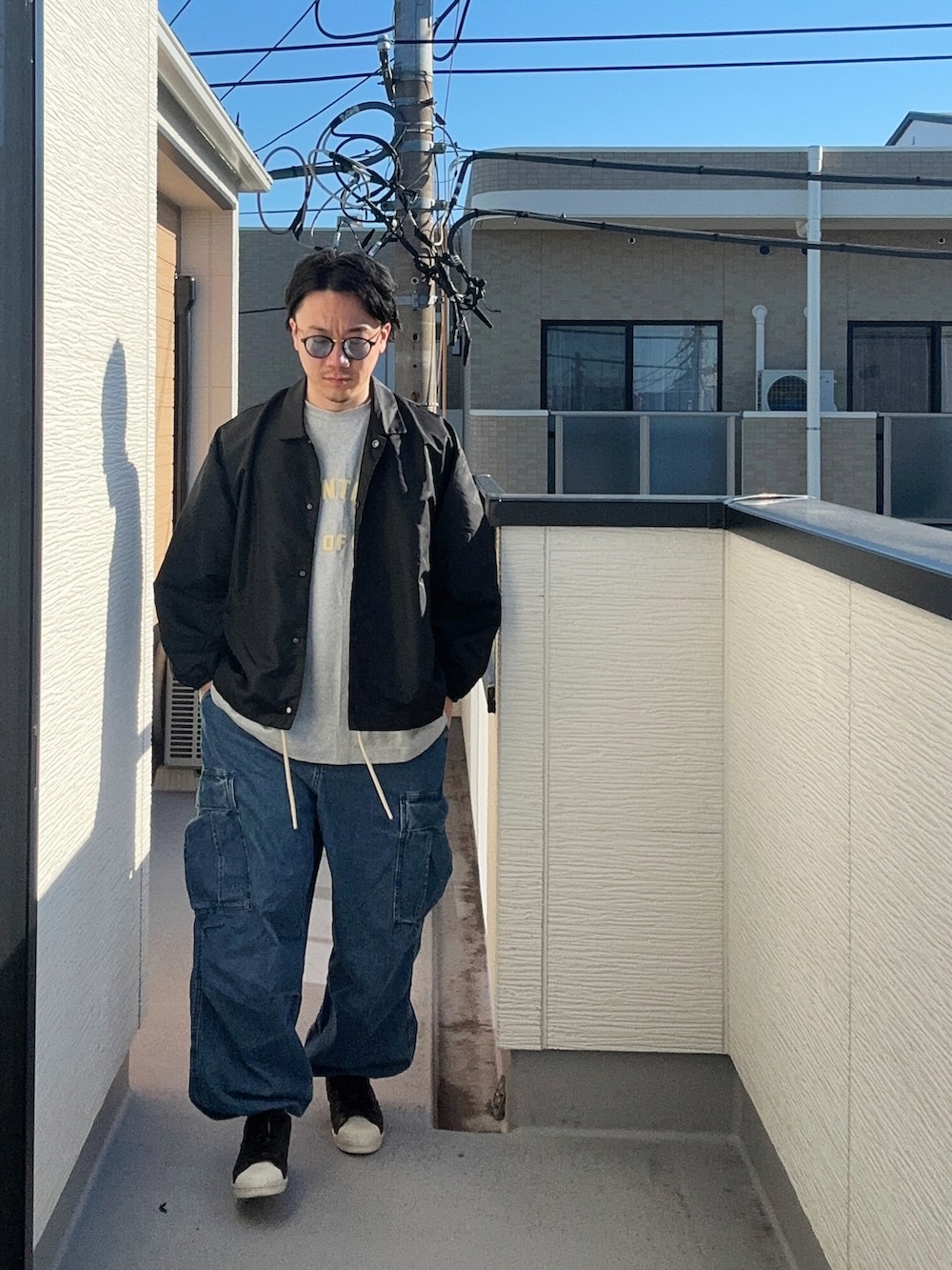 グレー系のTシャツ/カットソー、ブラック系のナイロンジャケット、ブルー系のカーゴパンツを着用したメンズの秋コーディネートの2枚目の写真