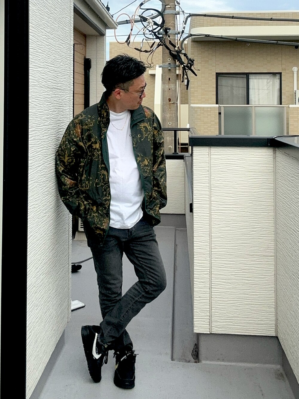 グレー系のデニムパンツ、ホワイト系のTシャツ/カットソー、ブラック系のスニーカーを着用したメンズの秋コーディネートの2枚目の写真