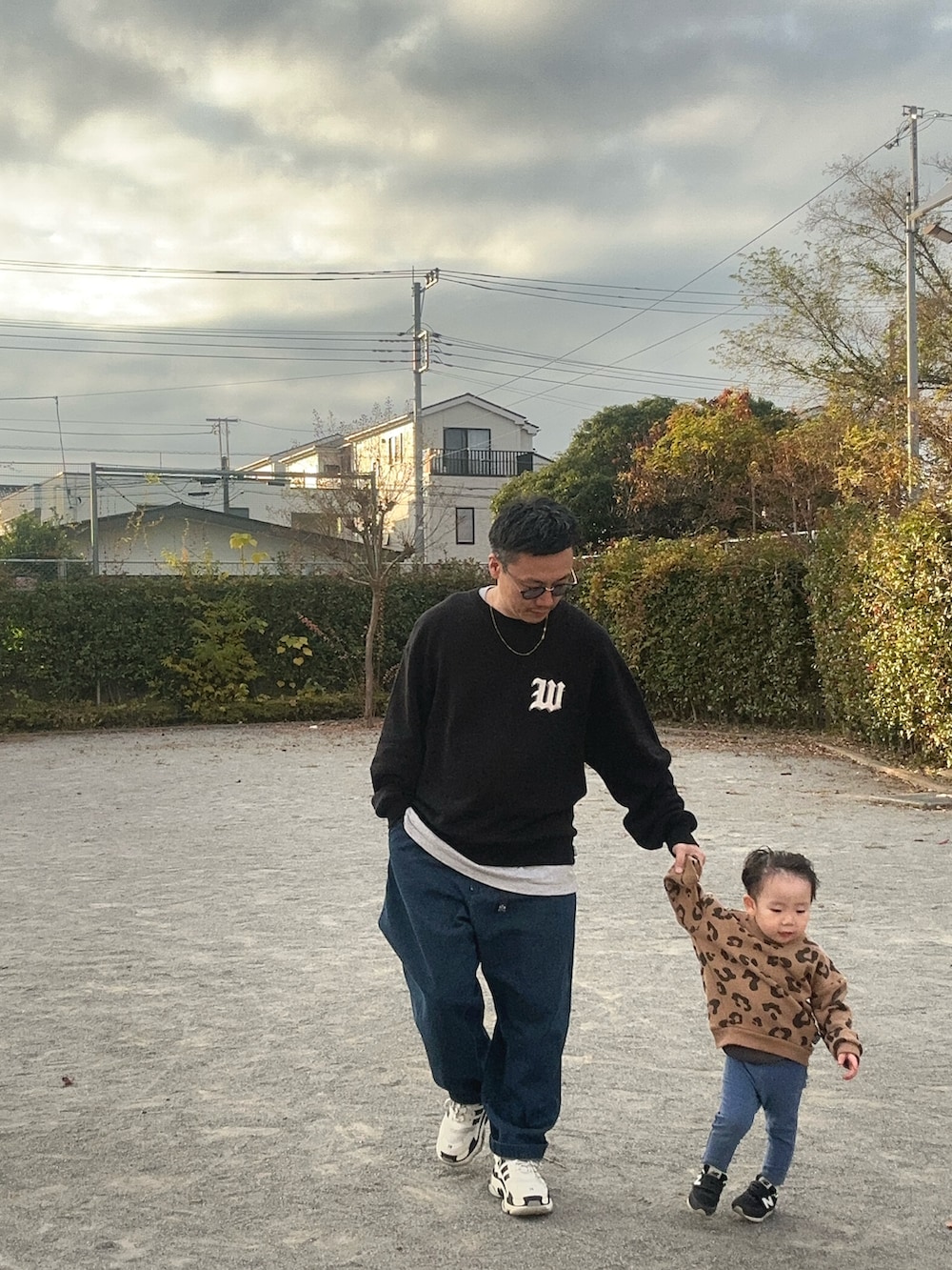 ブルー系のデニムパンツ、ブラック系のスニーカー、ブラック系のスウェットを着用したメンズの秋コーディネートの2枚目の写真