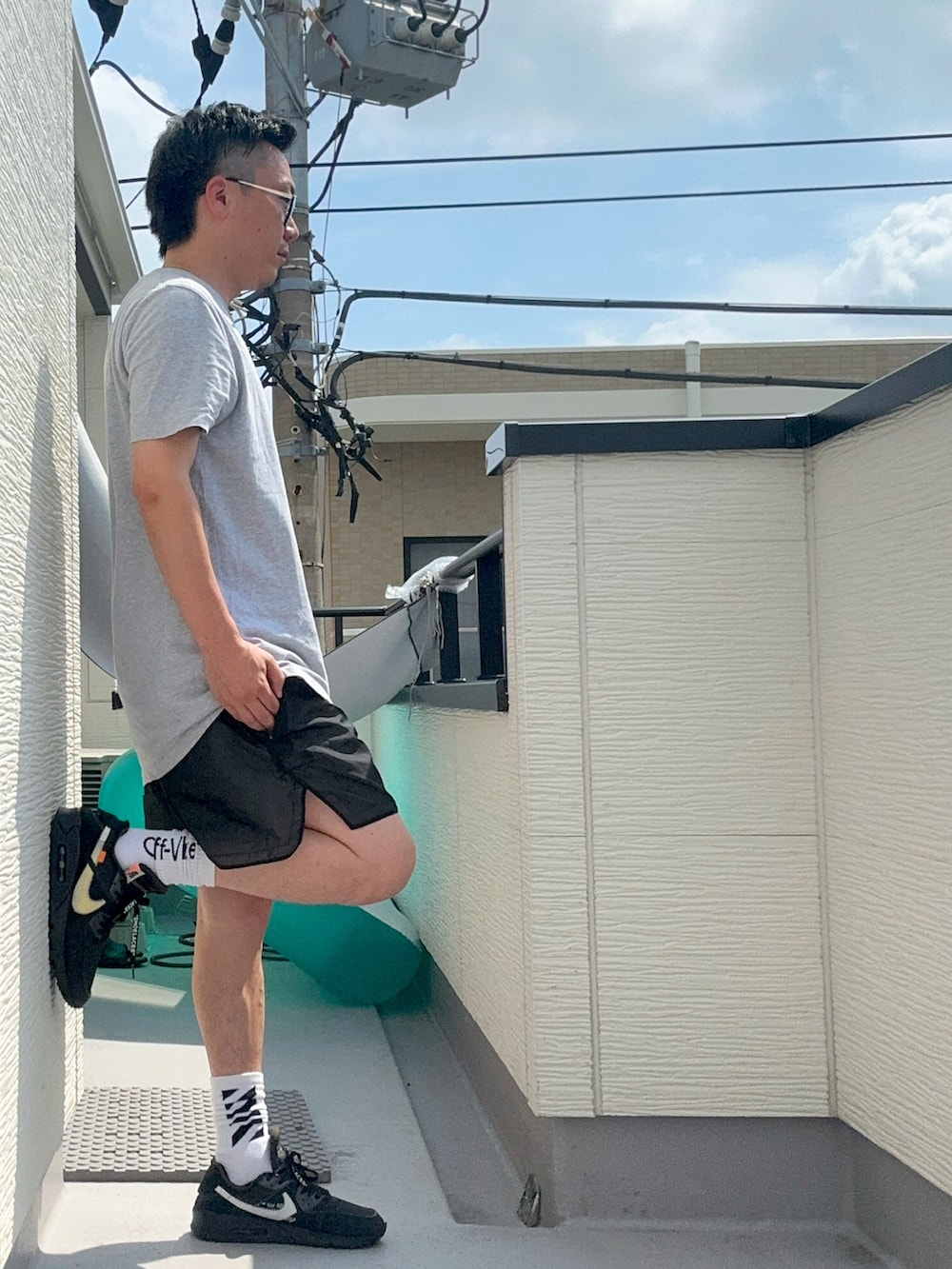 グレー系のTシャツ/カットソー、ブラック系のパンツ、ブラック系のスニーカーを着用したメンズの夏コーディネートの2枚目の写真