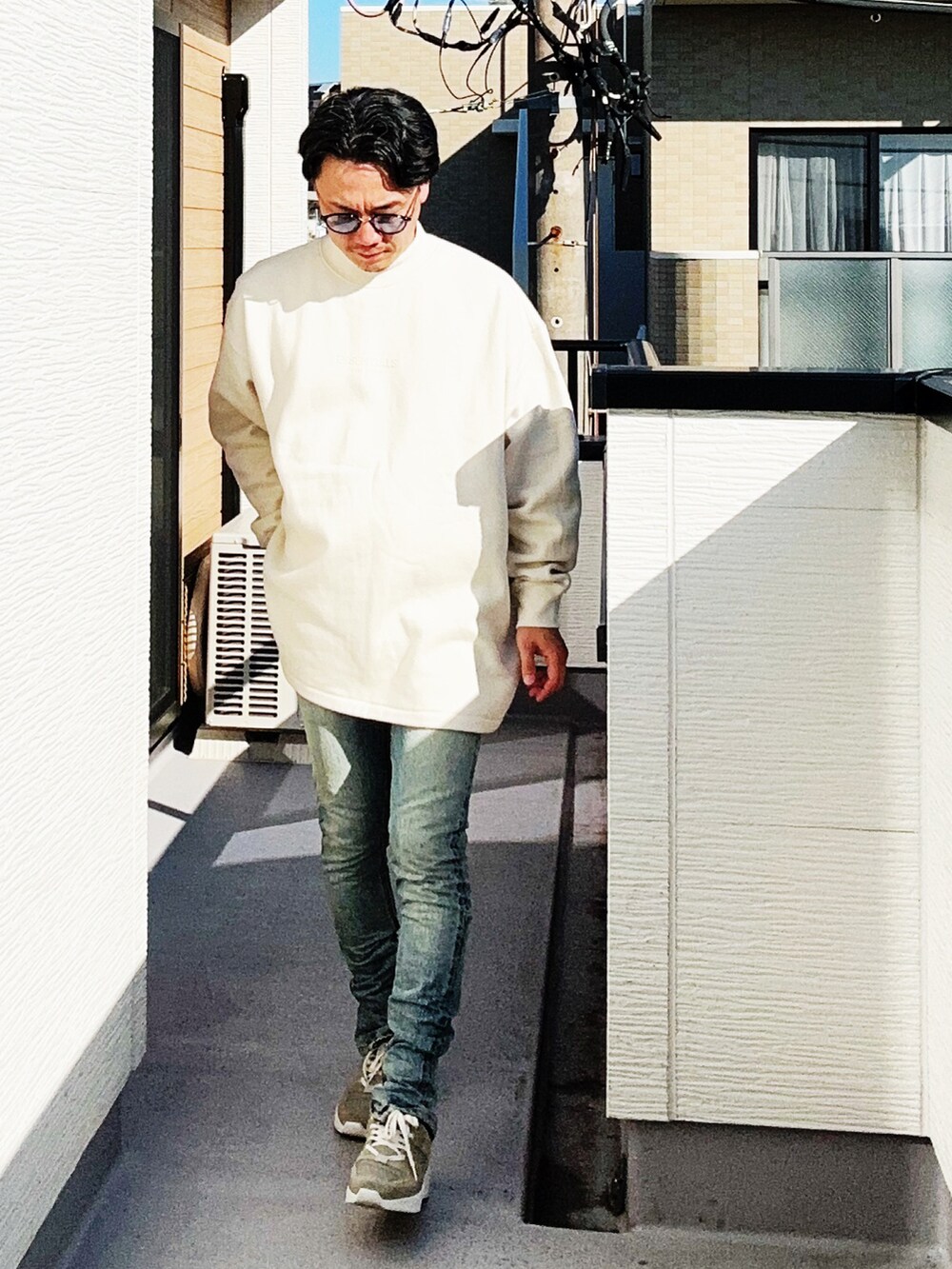 ベージュ系のスウェット、グレー系のスニーカー、ブルー系のデニムパンツを着用したメンズの秋コーディネートの3枚目の写真