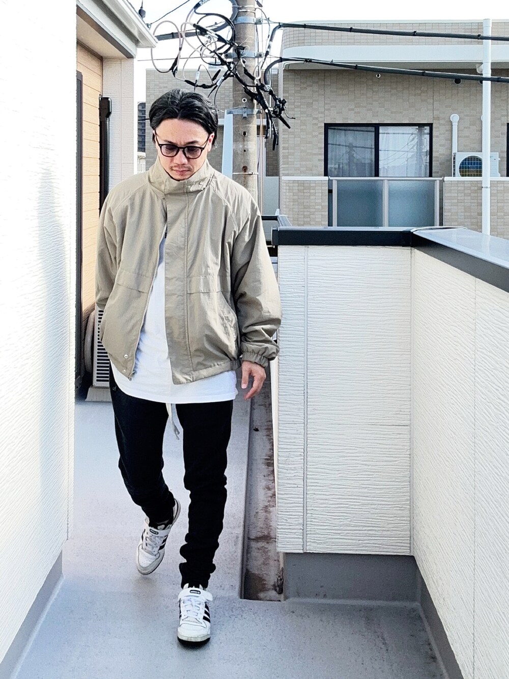 ベージュ系のブルゾン、ホワイト系のTシャツ/カットソー、ブラック系のパンツを着用したメンズの秋コーディネートの2枚目の写真