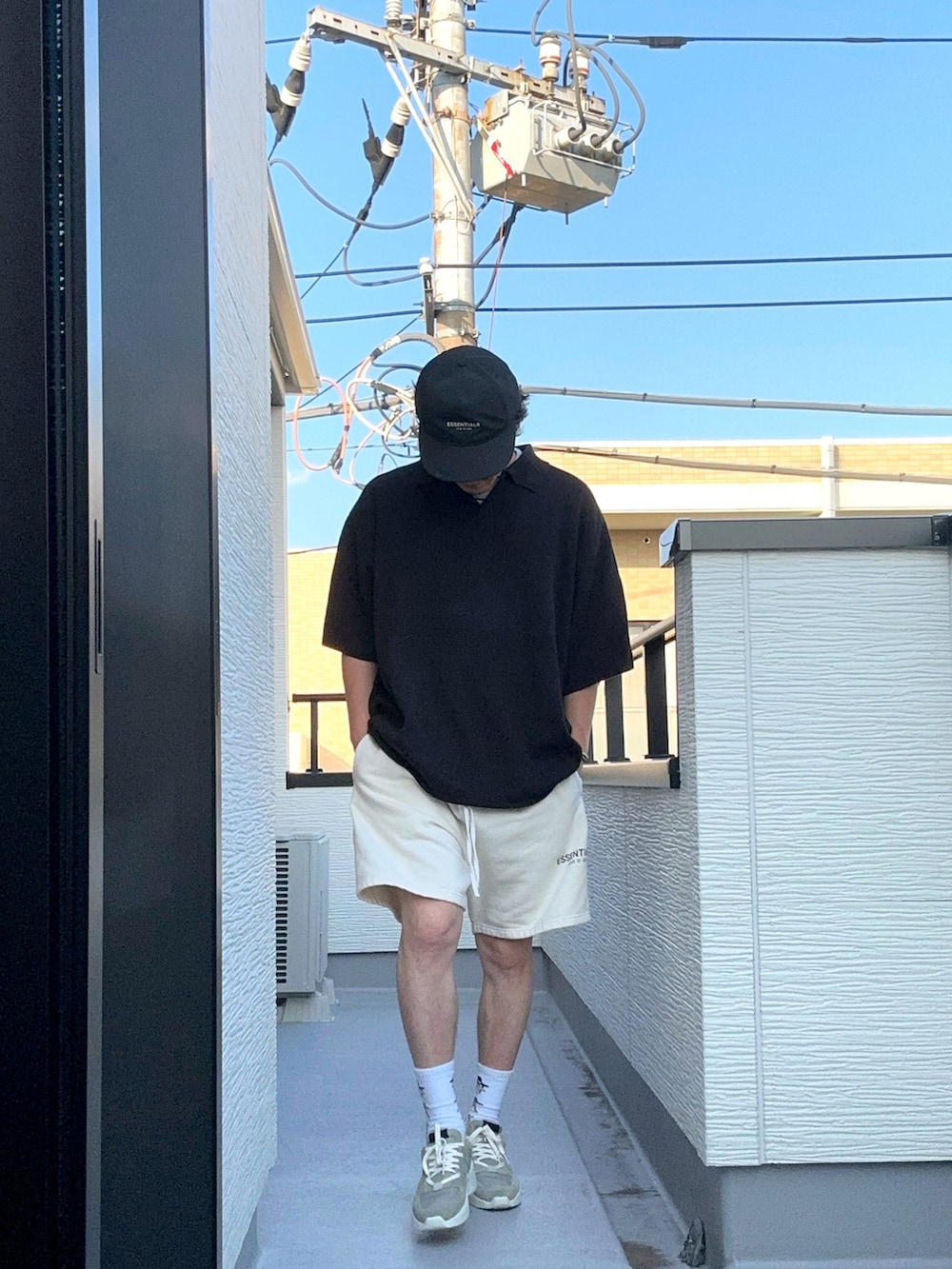 ホワイト系のスウェットパンツ、ブラック系のポロシャツ、グレー系のスニーカーを着用したメンズの夏コーディネートの2枚目の写真