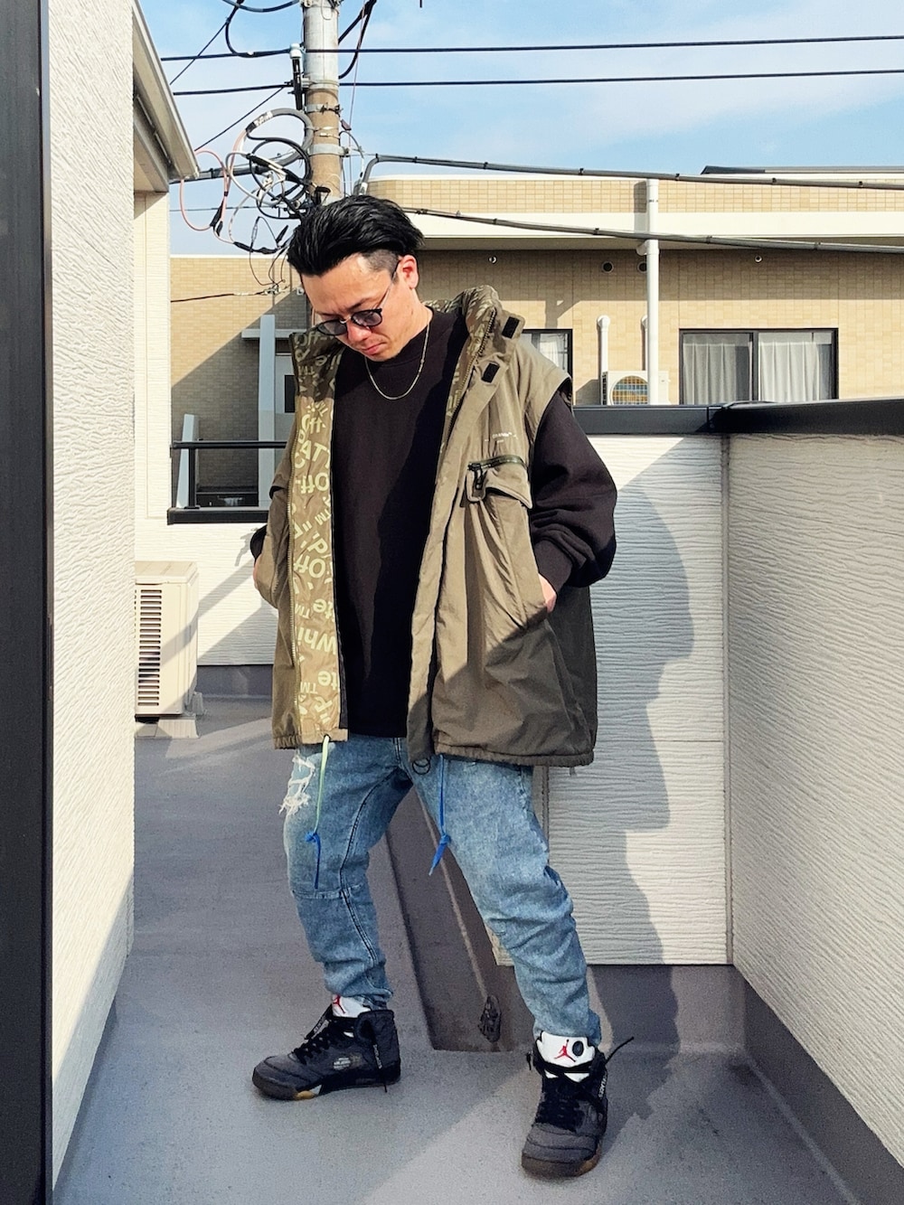 ブラック系のスウェット、ブルー系のデニムパンツ、グリーン系のミリタリージャケットを着用したメンズの冬コーディネートの3枚目の写真