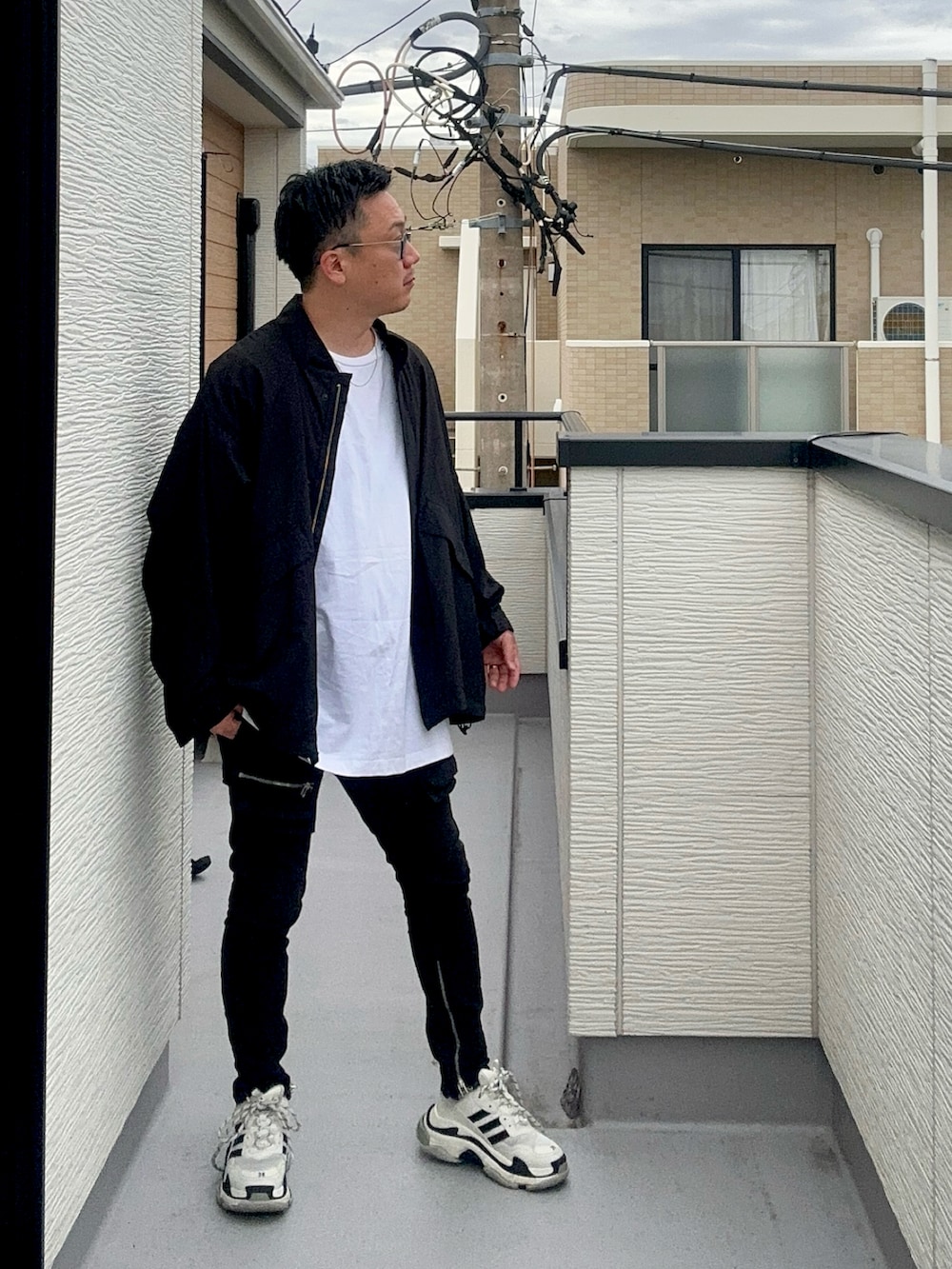 ブラック系のブルゾン、ホワイト系のトップス、ブラック系のデニムパンツを着用したメンズの秋コーディネートの3枚目の写真