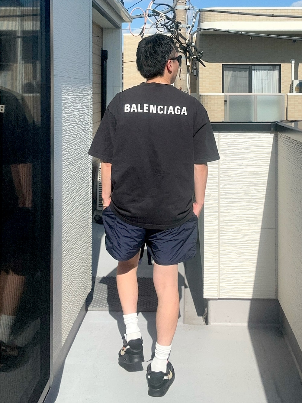 ブラック系のTシャツ/カットソー、ブルー系のパンツ、ブラック系のスニーカーを着用したメンズの秋コーディネートの2枚目の写真