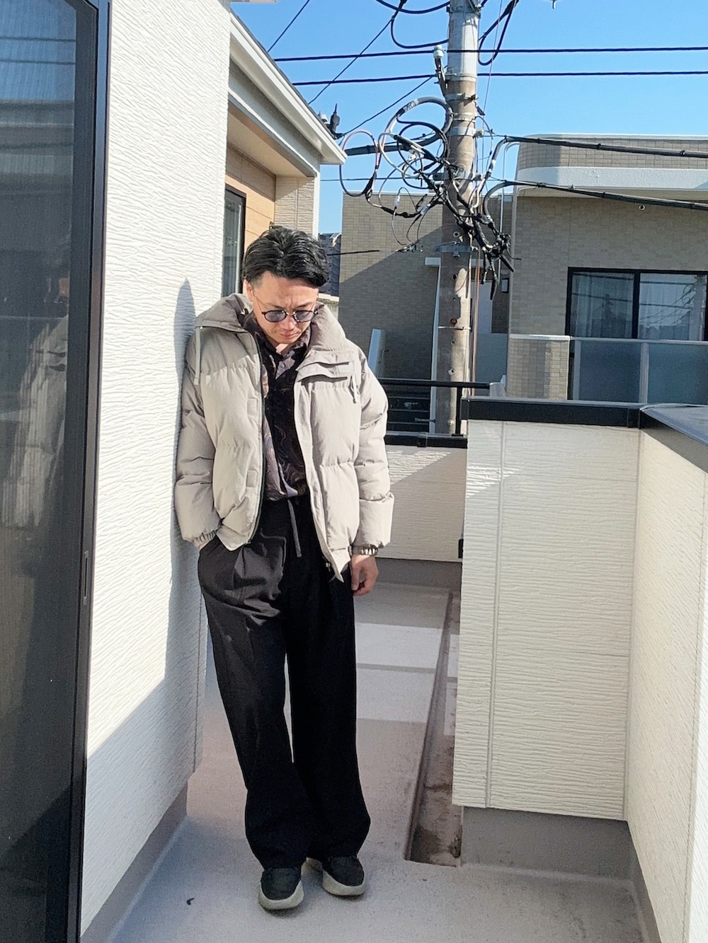 ブルー系のシャツ/ブラウス、グレー系のダウンジャケット/コート、ブラック系のスラックスを着用したメンズの冬コーディネートの3枚目の写真