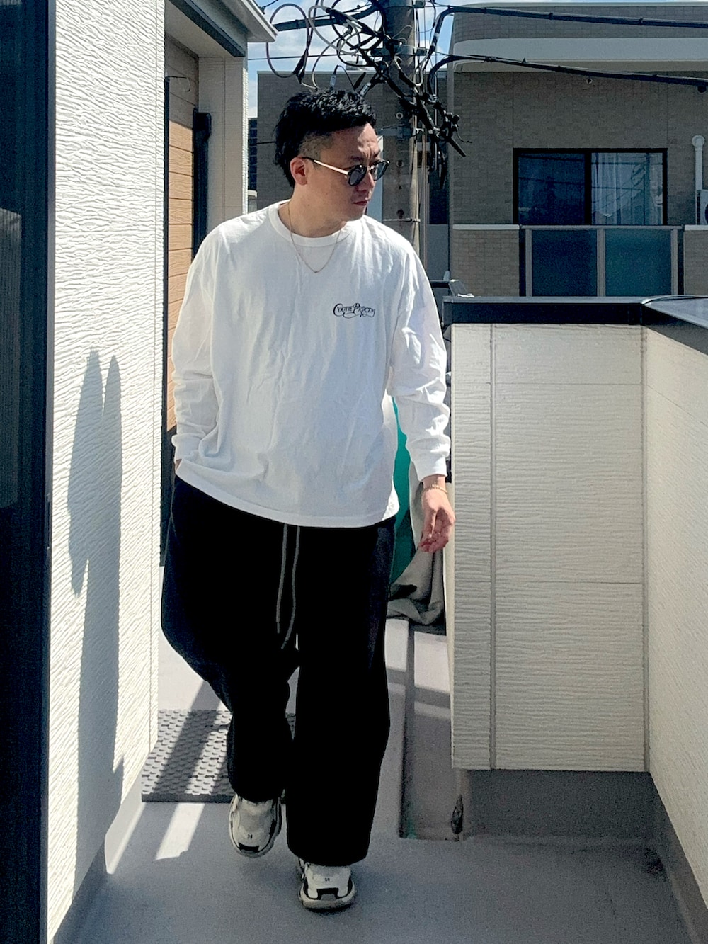 ブラック系のスウェットパンツ、ホワイト系のTシャツ/カットソー、ホワイト系のシューズを着用したメンズの秋コーディネートの2枚目の写真