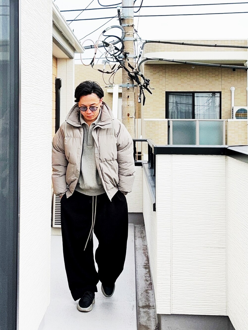 グレー系のポロシャツ、グレー系のダウンジャケット/コート、ブラック系のスウェットパンツを着用したメンズの冬コーディネートの2枚目の写真