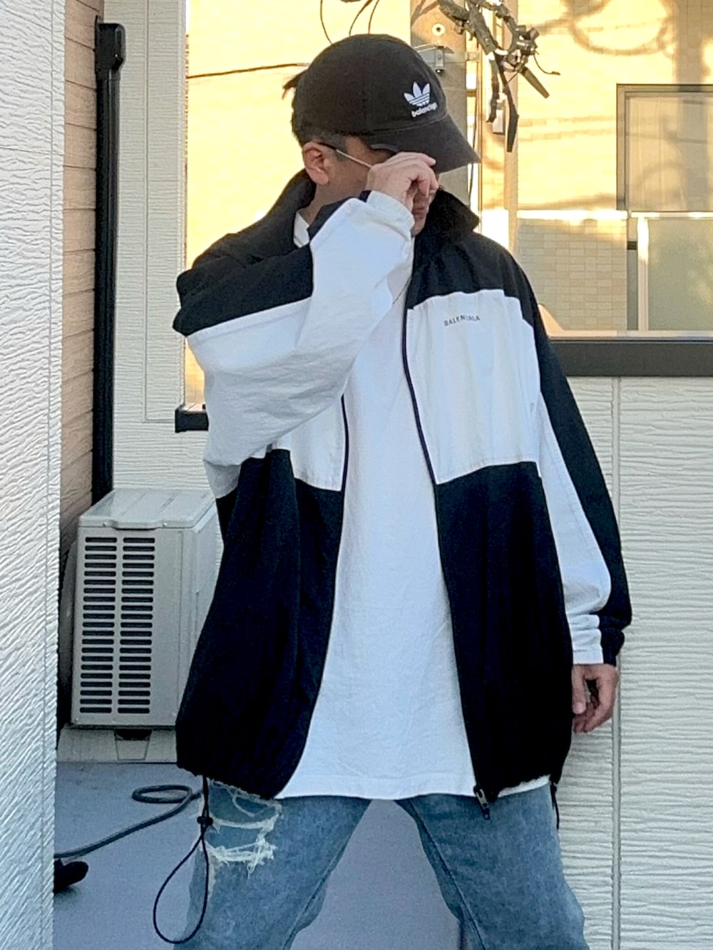 ブルー系のデニムパンツ、ホワイト系のトップス、ブラック系のナイロンジャケットを着用したメンズの秋コーディネートの5枚目の写真