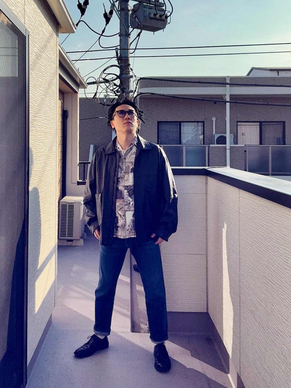 ブラック系のブルゾン、ブルー系のデニムパンツ、ベージュ系のシャツ/ブラウスを着用したメンズの春コーディネートの2枚目の写真