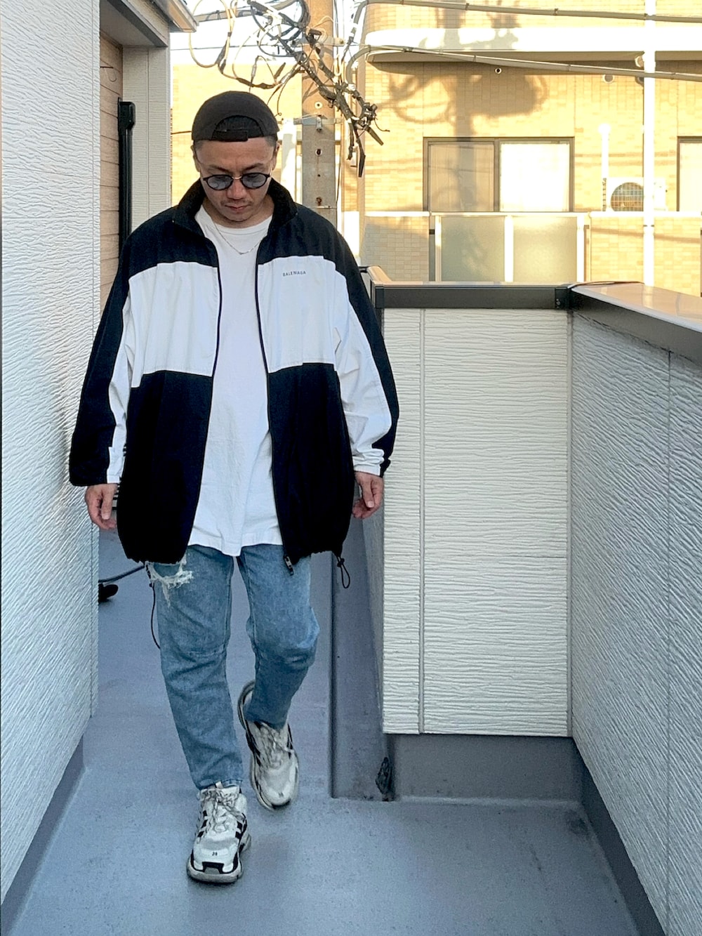 ブルー系のデニムパンツ、ホワイト系のトップス、ブラック系のナイロンジャケットを着用したメンズの秋コーディネートの2枚目の写真