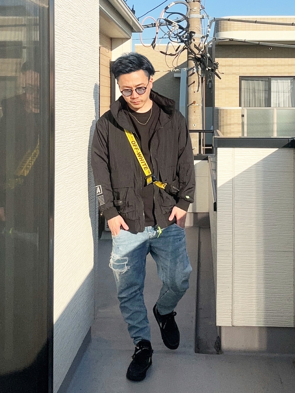 ブルー系のデニムパンツ、ブラック系のショルダーバッグ、ブラック系のTシャツ/カットソーを着用したメンズの冬コーディネートの2枚目の写真