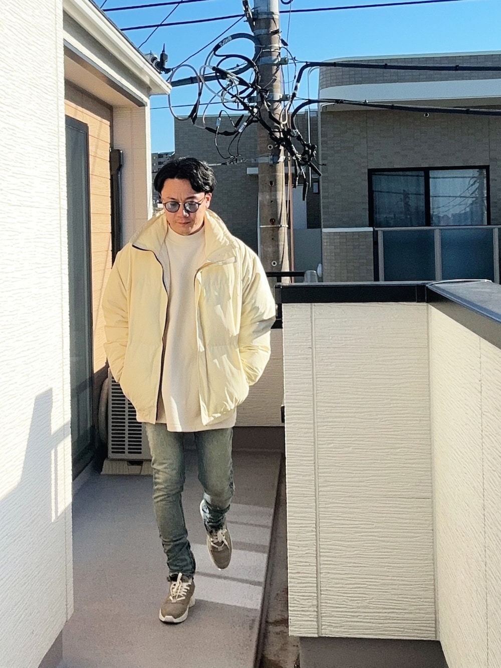 ベージュ系のダウンジャケット/コート、ベージュ系のスウェット、ブルー系のデニムパンツを着用したメンズの冬コーディネートの2枚目の写真