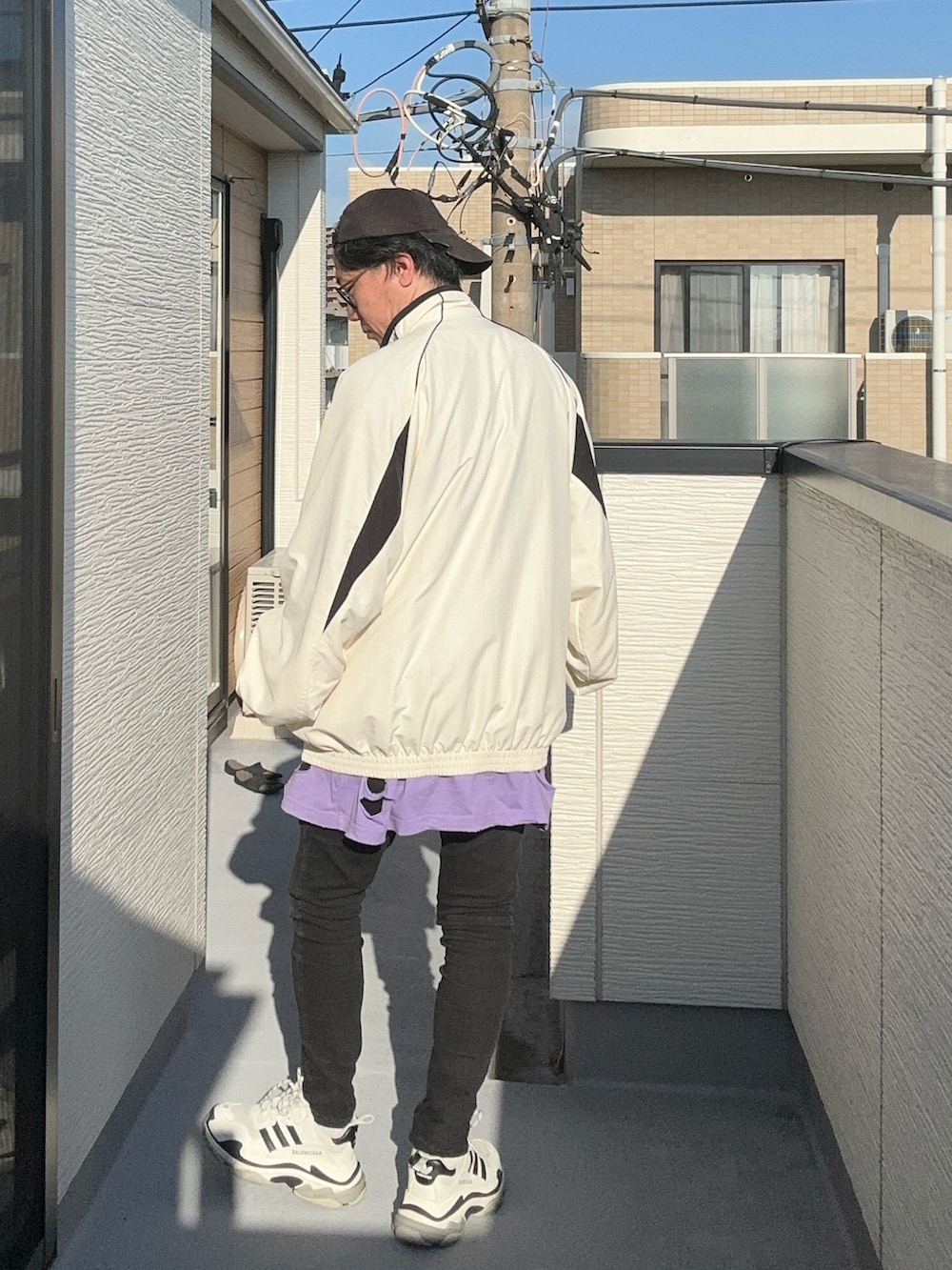 パープル系のTシャツ/カットソー、ホワイト系のナイロンジャケット、ブラック系のデニムパンツを着用したメンズの秋コーディネートの4枚目の写真