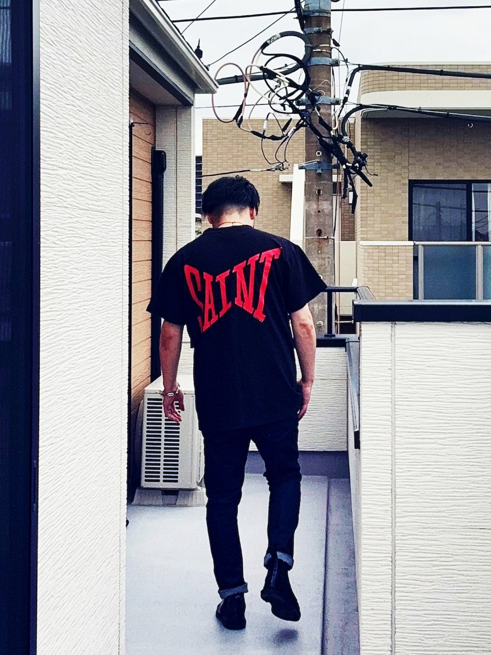 ブラック系のTシャツ/カットソー、ブルー系のデニムパンツ、ブラック系のブーツを着用したメンズの夏コーディネートの2枚目の写真