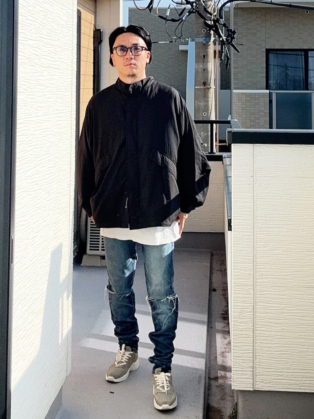 ブラック系のブルゾン、ホワイト系のTシャツ/カットソー、ブルー系のデニムパンツを着用したメンズの秋コーディネートの2枚目の写真