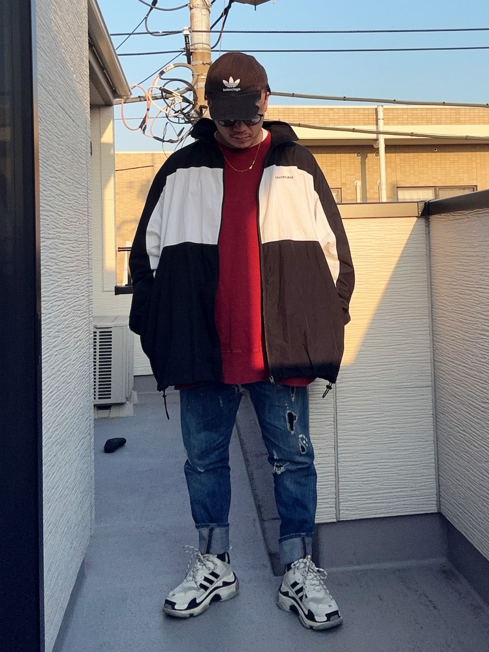 レッド系のスウェット、ブルー系のデニムパンツ、ブラック系のナイロンジャケットを着用したメンズの冬コーディネートの3枚目の写真