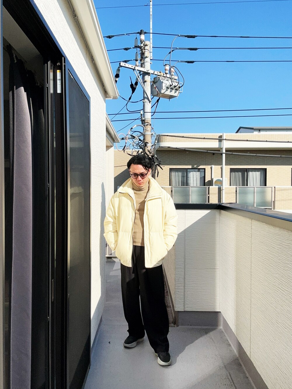 ベージュ系のニット/セーター、ベージュ系のダウンジャケット/コート、ブラック系のスラックスを着用したメンズの冬コーディネートの5枚目の写真