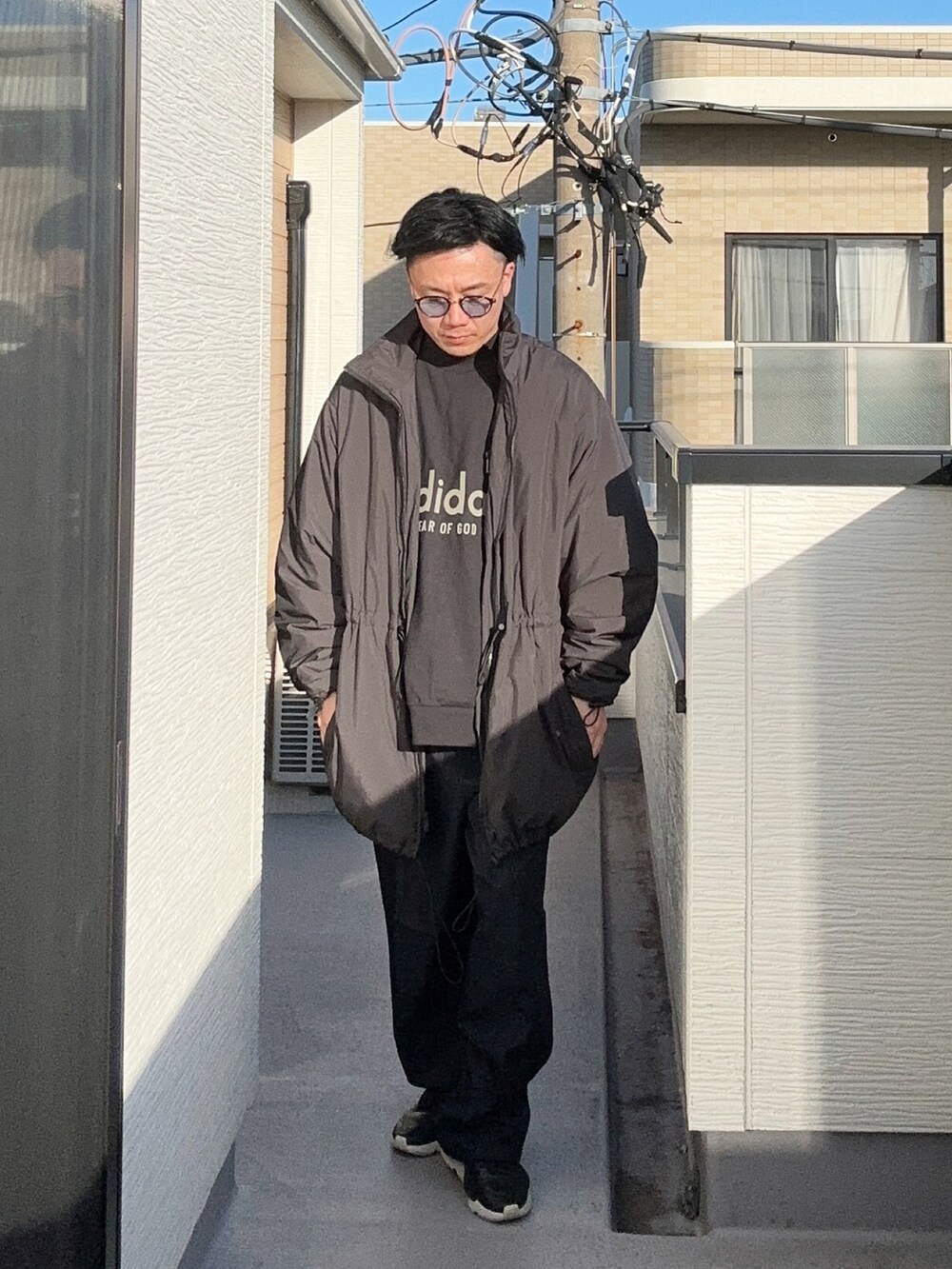 ブラック系のスウェット、ブルー系のスラックス、ブラック系のスニーカーを着用したメンズの冬コーディネートの2枚目の写真