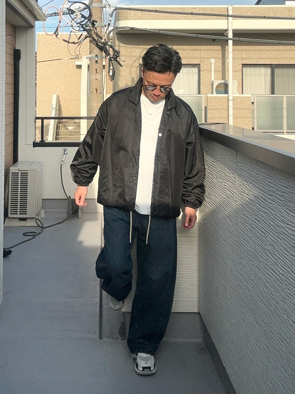 ブラック系のナイロンジャケット、ホワイト系のTシャツ/カットソー、ブルー系のデニムパンツを着用したメンズの秋コーディネートの2枚目の写真