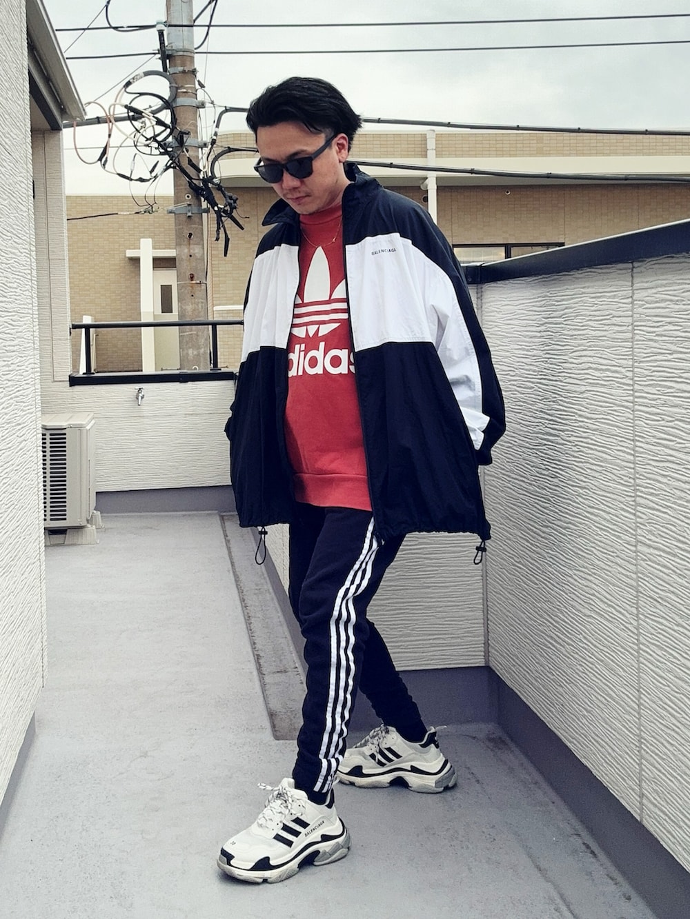 オレンジ系のスウェット、ブラック系のスウェットパンツ、ブラック系のナイロンジャケットを着用したメンズの冬コーディネートの3枚目の写真