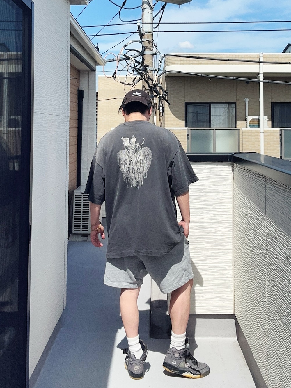 ブラック系のTシャツ/カットソー、グレー系のパンツ、グレー系のスニーカーを着用したメンズの夏コーディネートの3枚目の写真