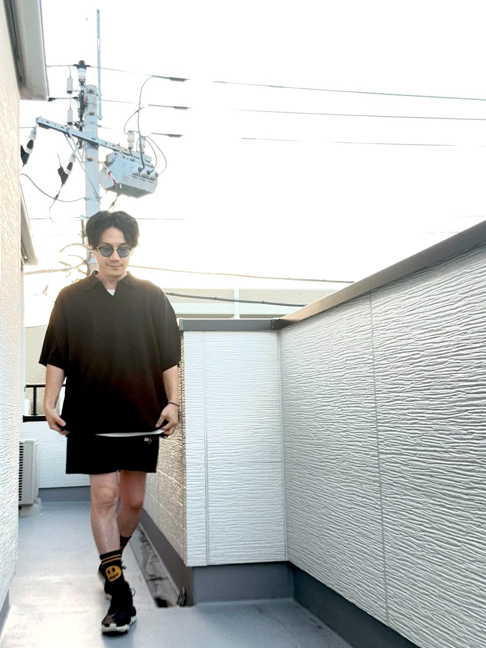 ブラック系のポロシャツ、ブラック系のスウェットパンツ、ブラック系のサンダルを着用したメンズの夏コーディネートの4枚目の写真