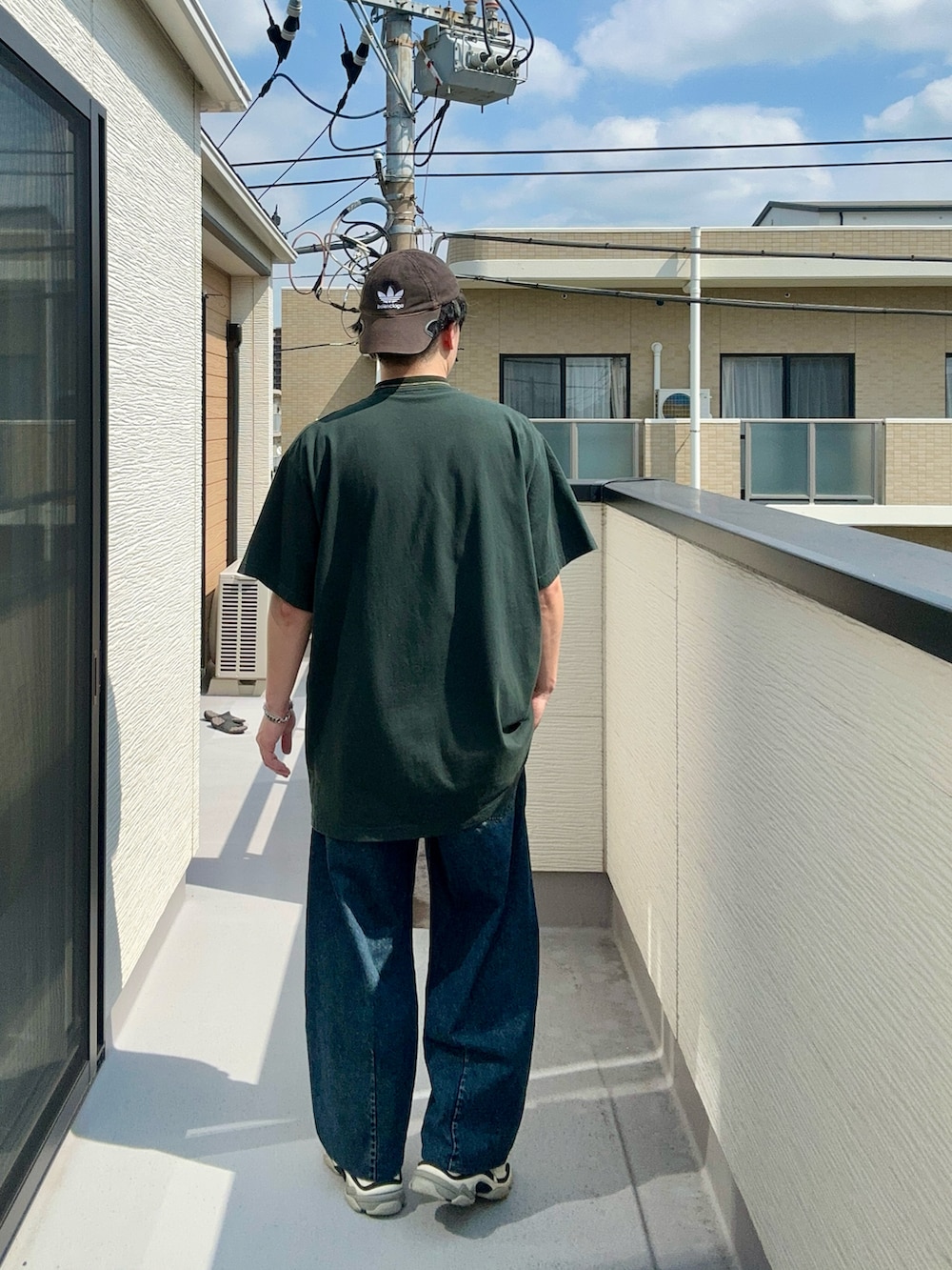 グリーン系のTシャツ/カットソー、ブルー系のデニムパンツ、ホワイト系のシューズを着用したメンズの秋コーディネートの4枚目の写真