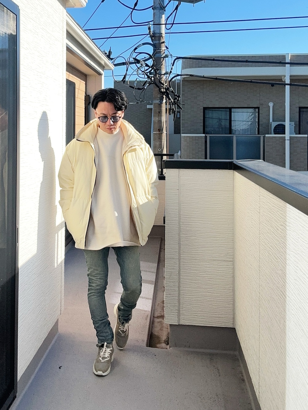 ベージュ系のダウンジャケット/コート、ベージュ系のスウェット、ブルー系のデニムパンツを着用したメンズの冬コーディネートの3枚目の写真