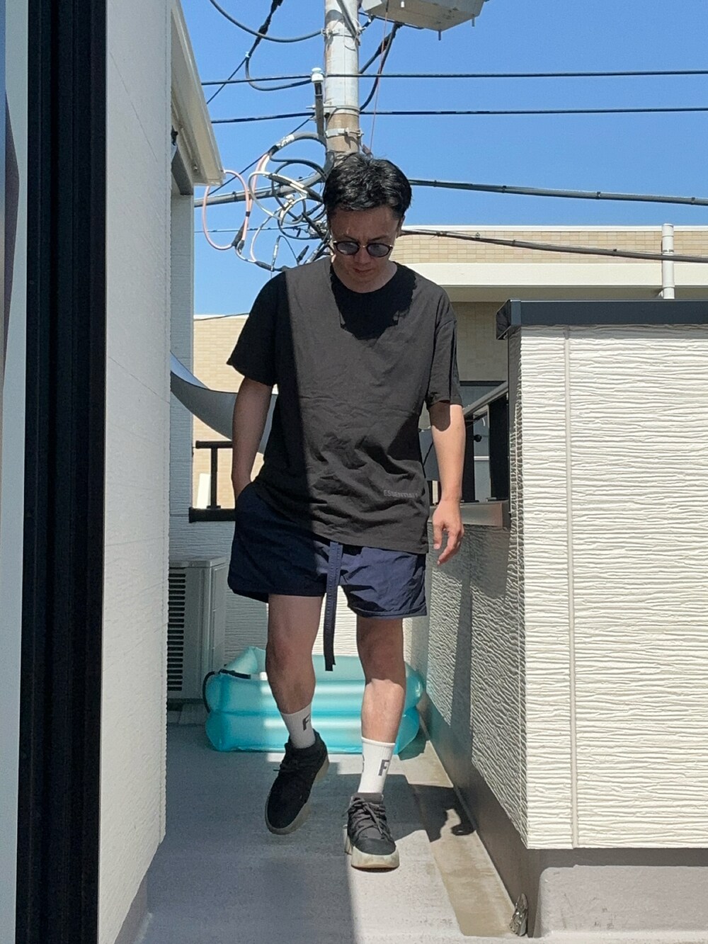 ブルー系のパンツ、ブラック系のTシャツ/カットソー、ブラック系のスニーカーを着用したメンズの夏コーディネートの2枚目の写真