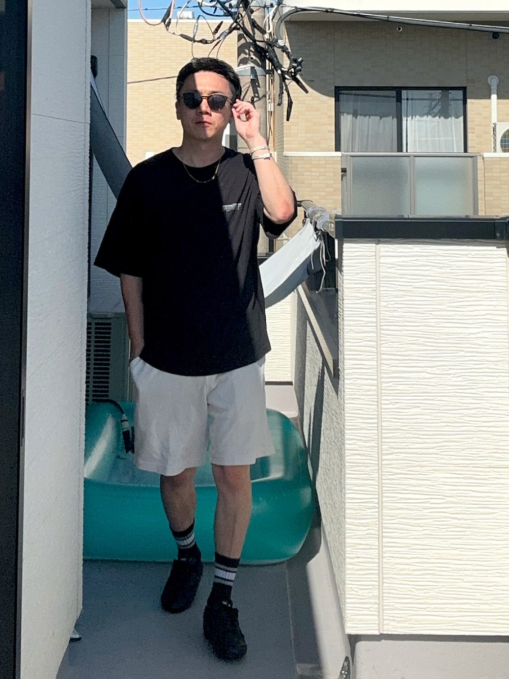 ブラック系のTシャツ/カットソー、ホワイト系のパンツ、ブラック系のシューズを着用したメンズの夏コーディネートの4枚目の写真