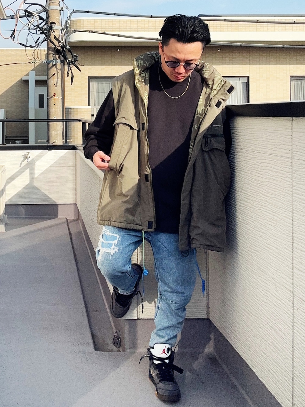 ブラック系のスウェット、ブルー系のデニムパンツ、グリーン系のミリタリージャケットを着用したメンズの冬コーディネートの4枚目の写真