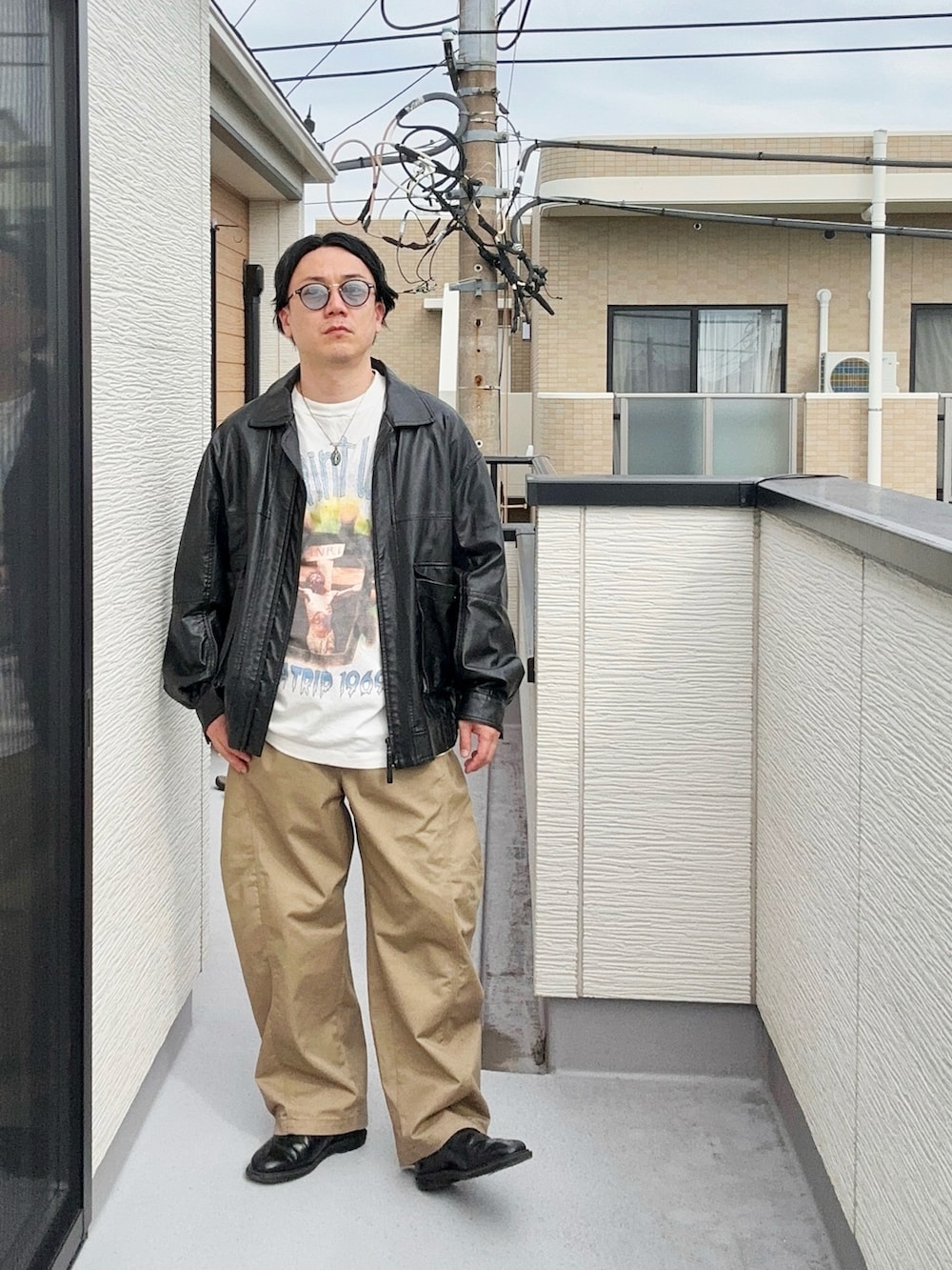 ブラック系のブルゾン、ホワイト系のTシャツ/カットソー、ベージュ系のパンツを着用したメンズの秋コーディネートの2枚目の写真