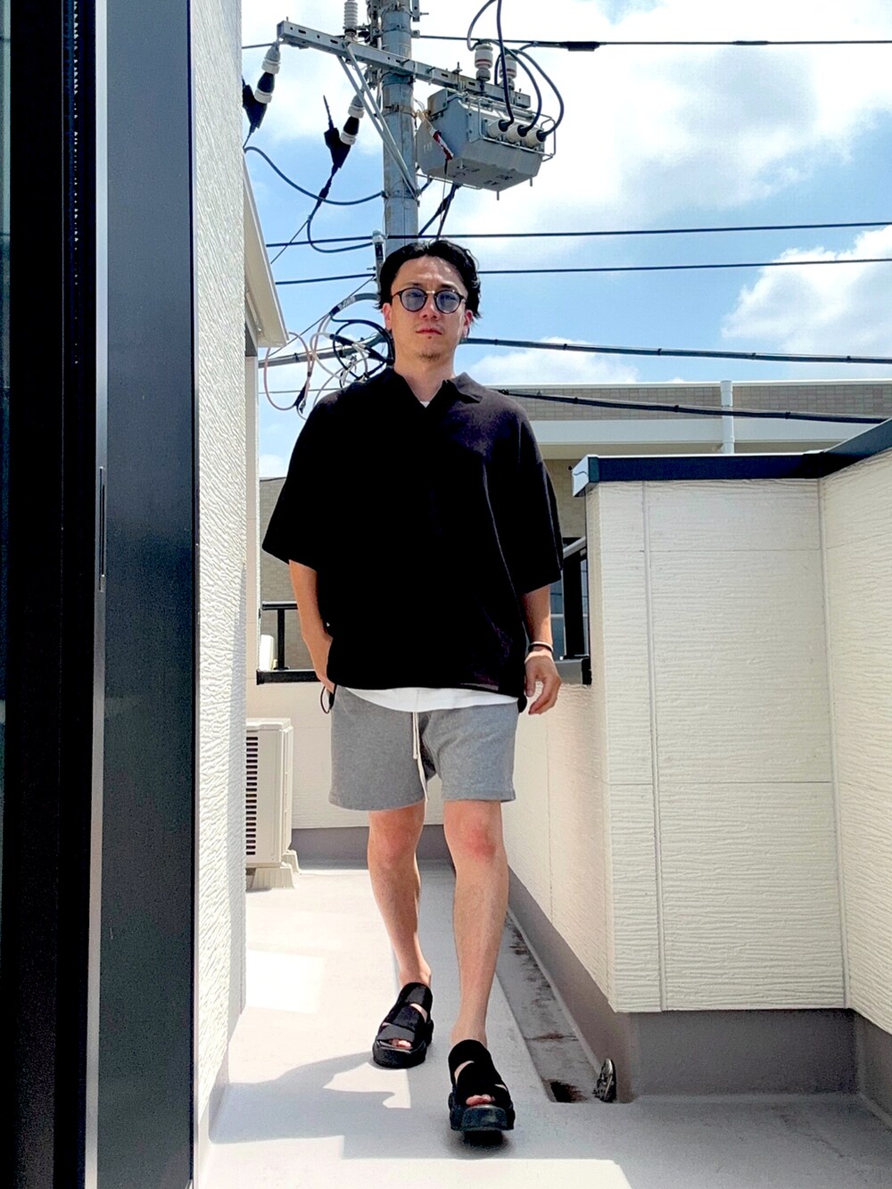 ブラック系のポロシャツ、グレー系のパンツ、ホワイト系のTシャツ/カットソーを着用したメンズの夏コーディネートの5枚目の写真