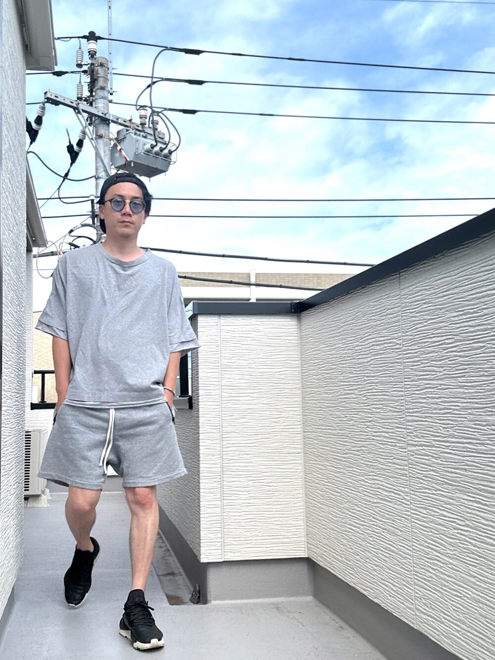グレー系のTシャツ/カットソー、グレー系のパンツ、ブラック系のスニーカーを着用したメンズの夏コーディネートの2枚目の写真