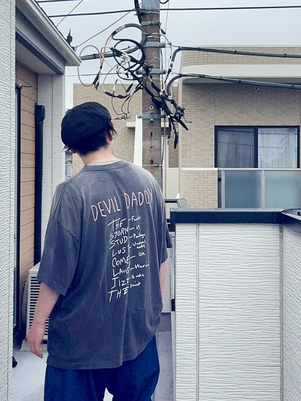 ブルー系のデニムパンツ、ブラック系のTシャツ/カットソー、ブラウン系のローファーを着用したメンズの夏コーディネートの5枚目の写真
