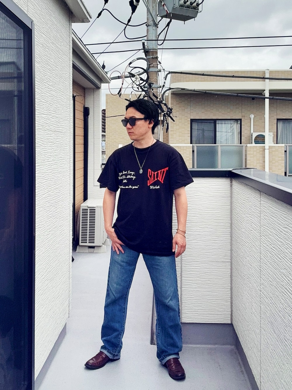 ブルー系のデニムパンツ、ブラック系のTシャツ/カットソー、ブラウン系のローファーを着用したメンズの夏コーディネートの2枚目の写真