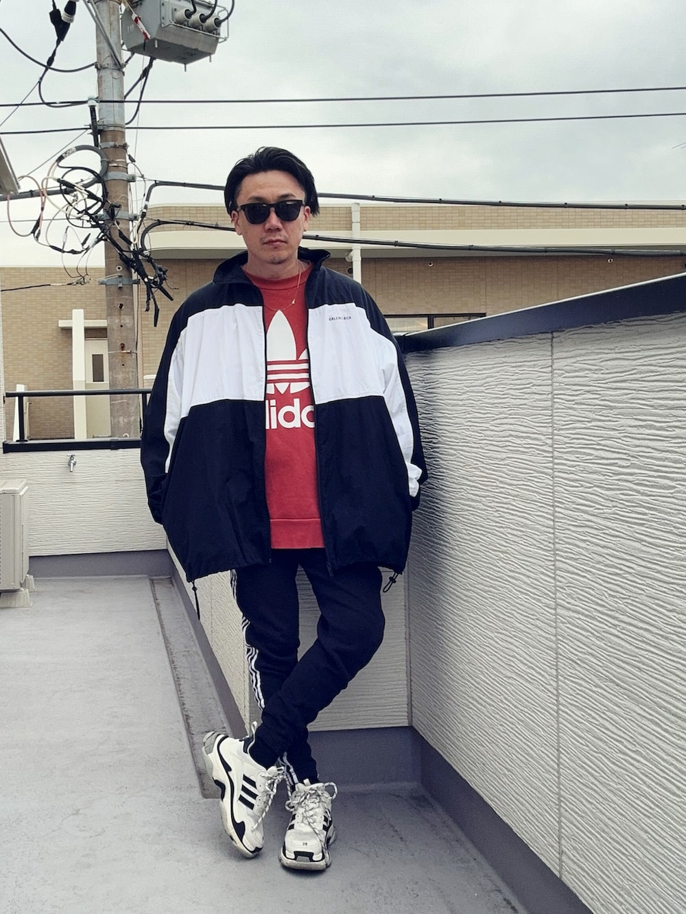 オレンジ系のスウェット、ブラック系のスウェットパンツ、ブラック系のナイロンジャケットを着用したメンズの冬コーディネートの2枚目の写真