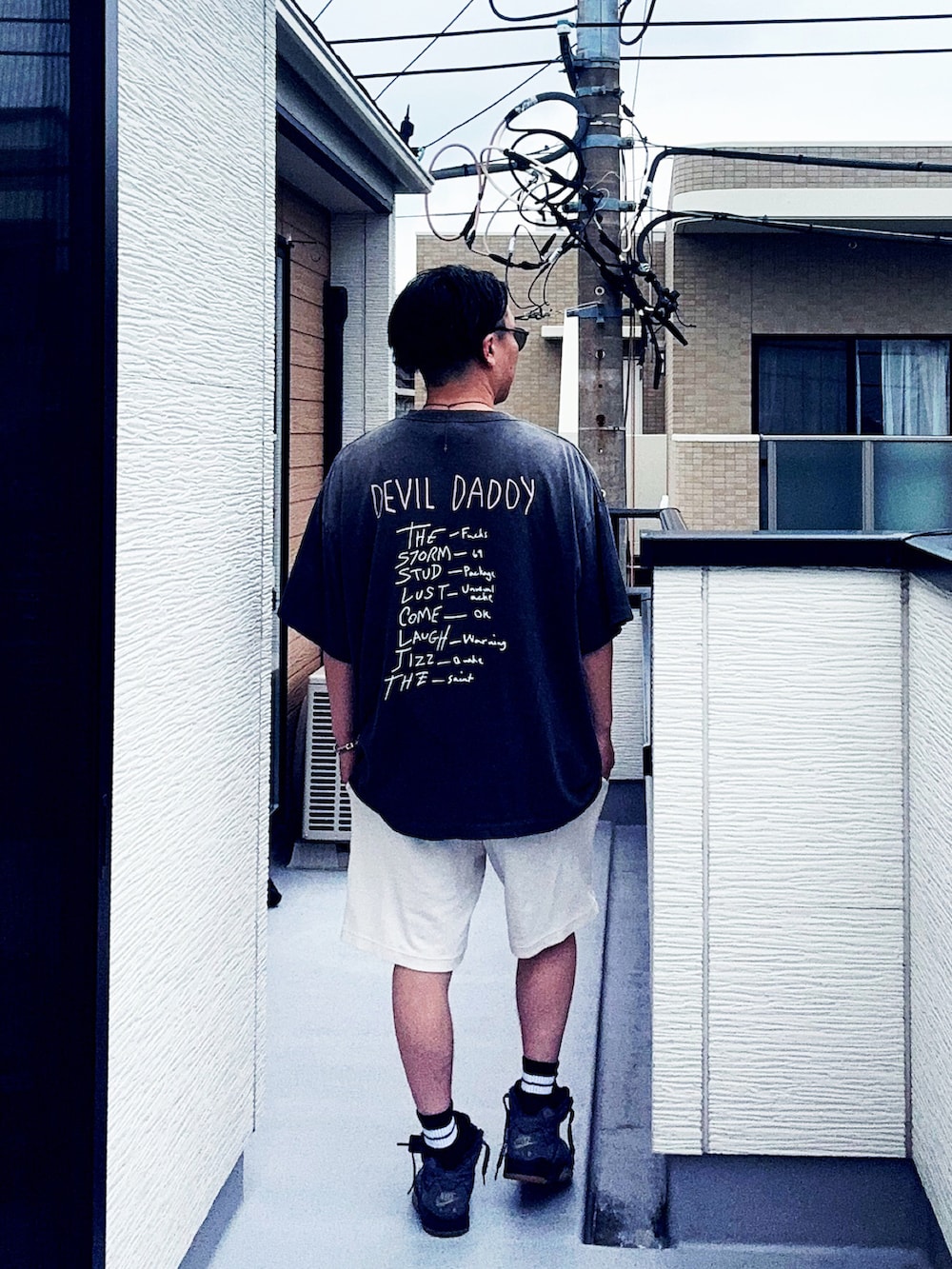 ブラック系のTシャツ/カットソー、ホワイト系のパンツ、グレー系のスニーカーを着用したメンズの夏コーディネートの3枚目の写真