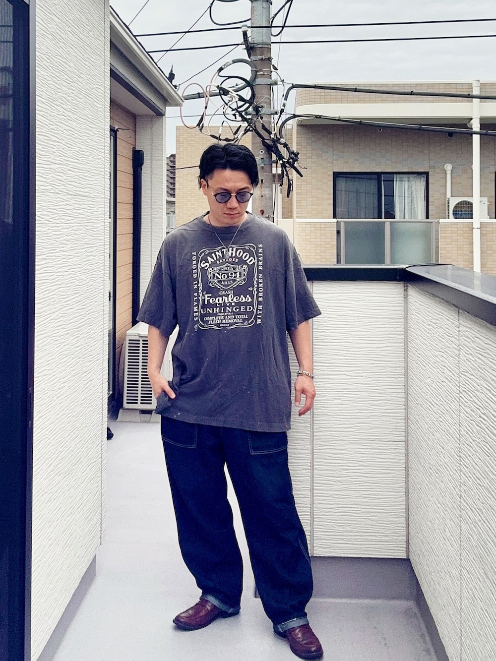 ブルー系のデニムパンツ、ブラック系のTシャツ/カットソー、ブラウン系のローファーを着用したメンズの夏コーディネートの2枚目の写真