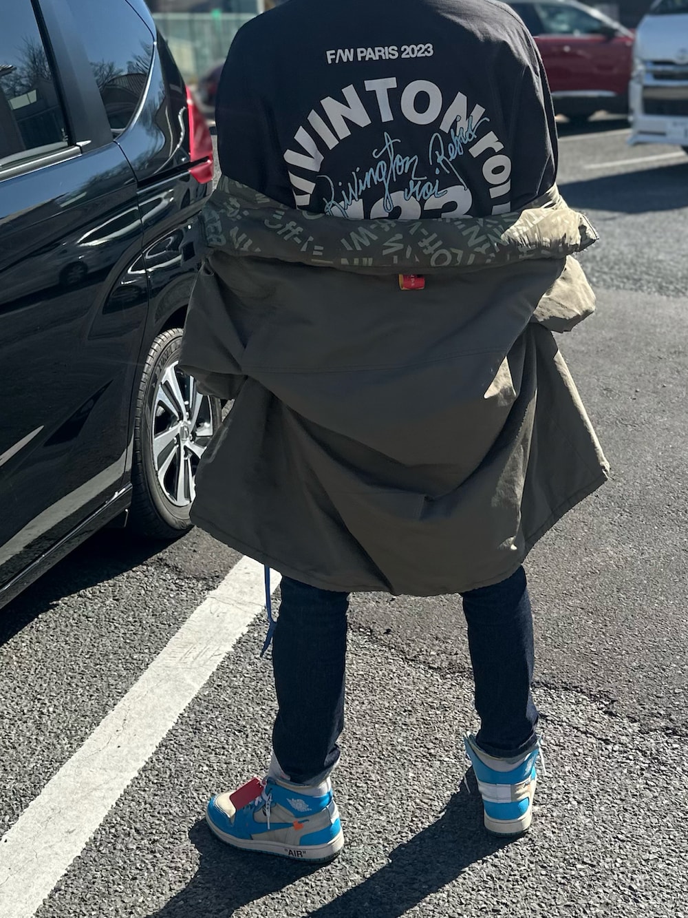 ブラック系のTシャツ/カットソー、グリーン系のミリタリージャケット、ブルー系のデニムパンツを着用したメンズの冬コーディネートの3枚目の写真