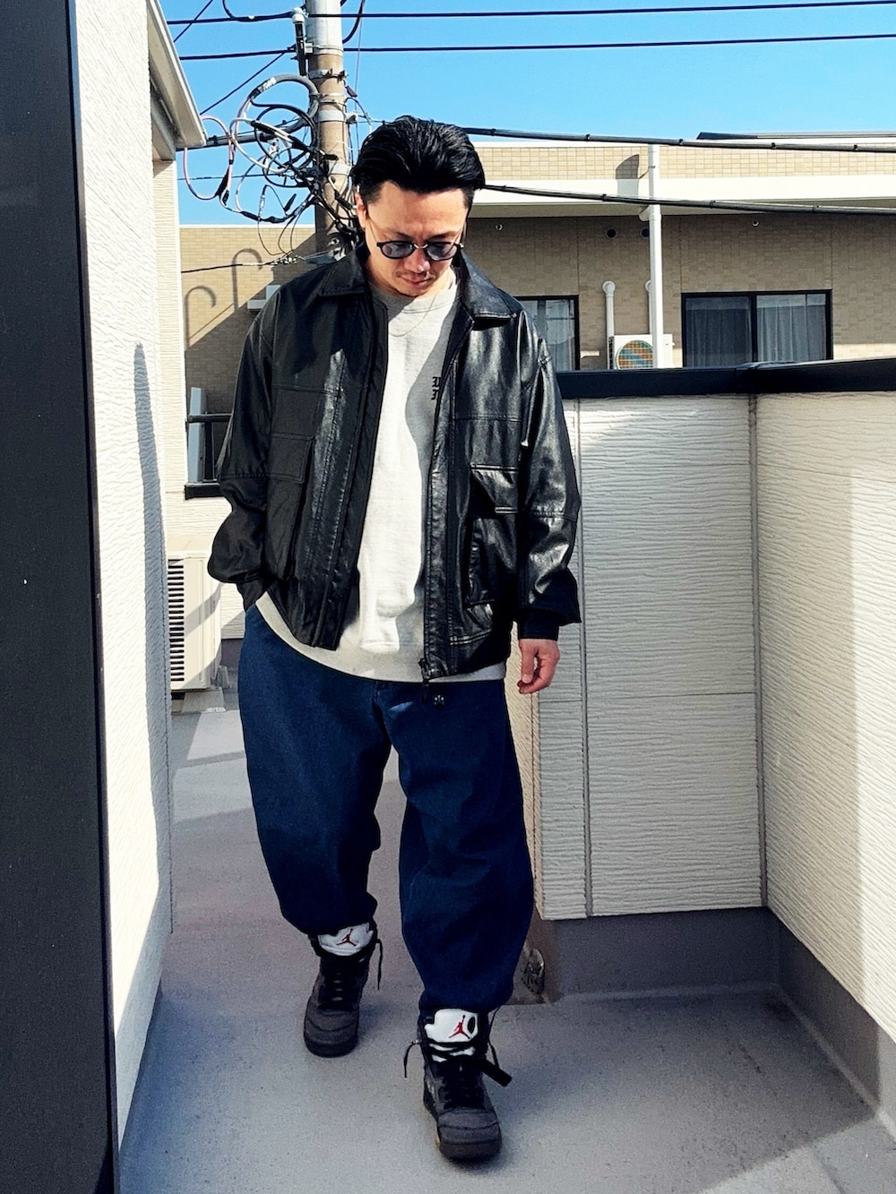 ブラック系のブルゾン、ブルー系のデニムパンツ、グレー系のスウェットを着用したメンズの冬コーディネートの2枚目の写真