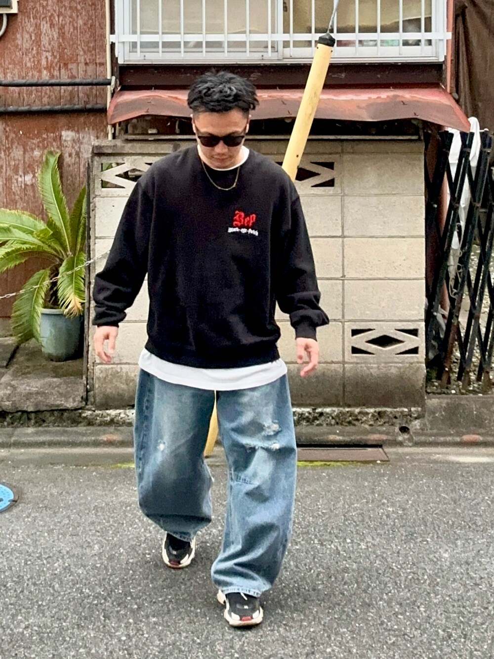 ブルー系のデニムパンツ、ブラック系のスウェット、ブラック系のスニーカーを着用したメンズの秋コーディネートの2枚目の写真