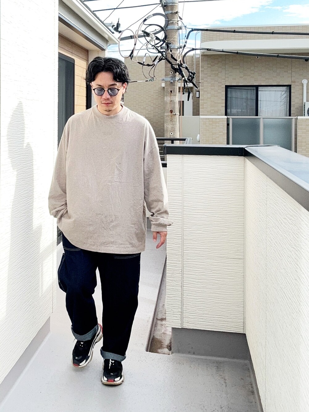 グレー系のTシャツ/カットソー、ブルー系のデニムパンツ、ブラック系のスニーカーを着用したメンズの秋コーディネートの2枚目の写真