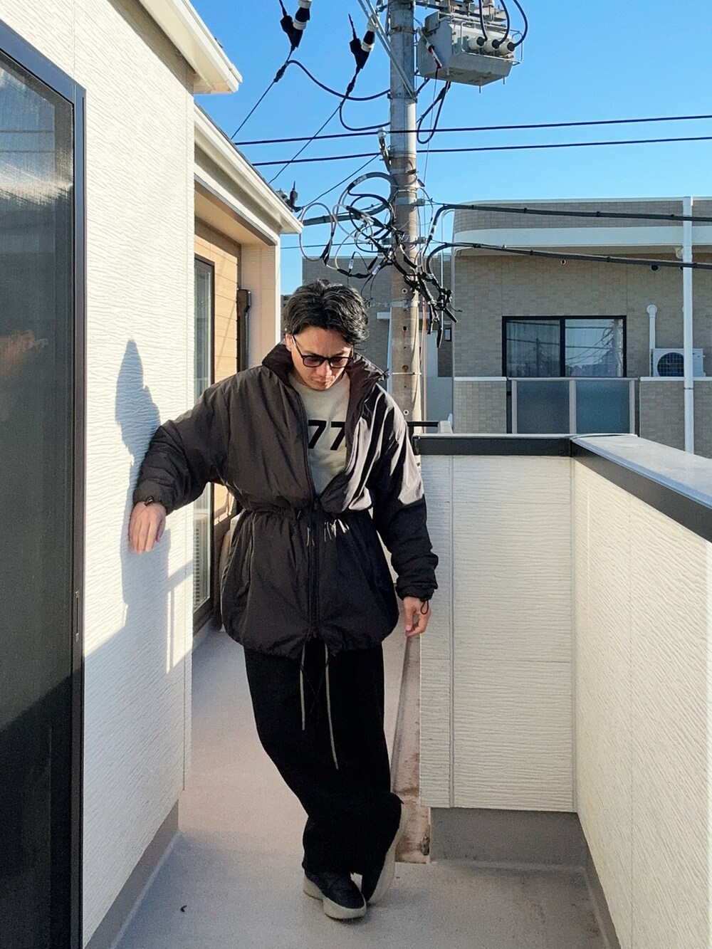 ブラック系のその他アウター、ホワイト系のニット/セーター、ブラック系のスウェットパンツを着用したメンズの冬コーディネートの2枚目の写真