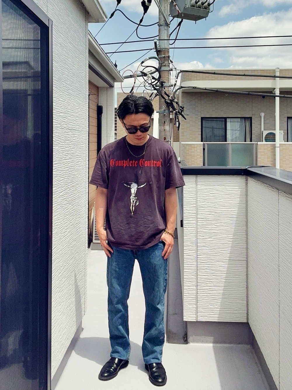 ブルー系のデニムパンツ、ブラック系のTシャツ/カットソー、ブラック系のブーツを着用したメンズの春コーディネートの2枚目の写真