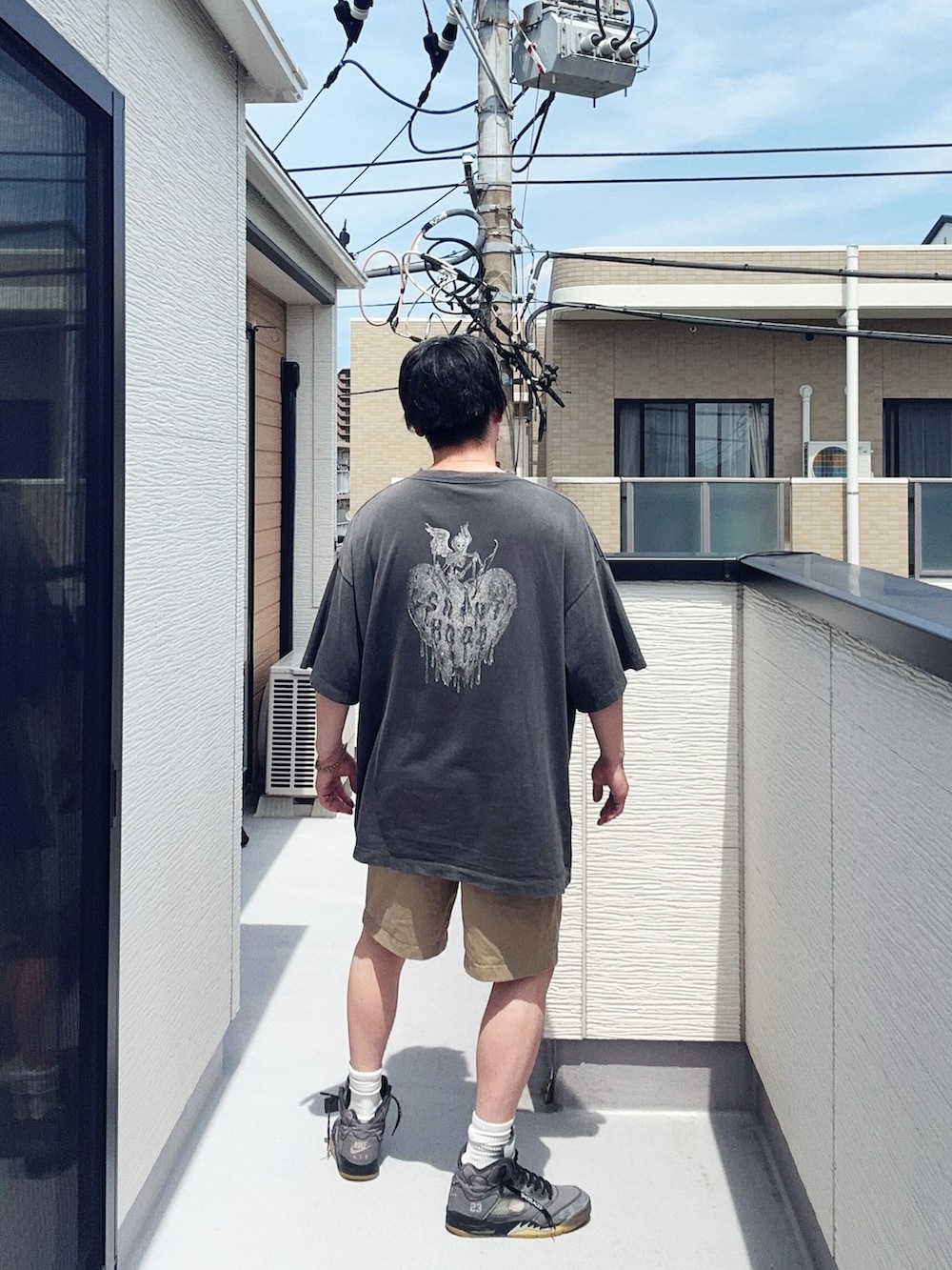 ブラック系のTシャツ/カットソー、ベージュ系のパンツ、グレー系のスニーカーを着用したメンズの夏コーディネートの3枚目の写真