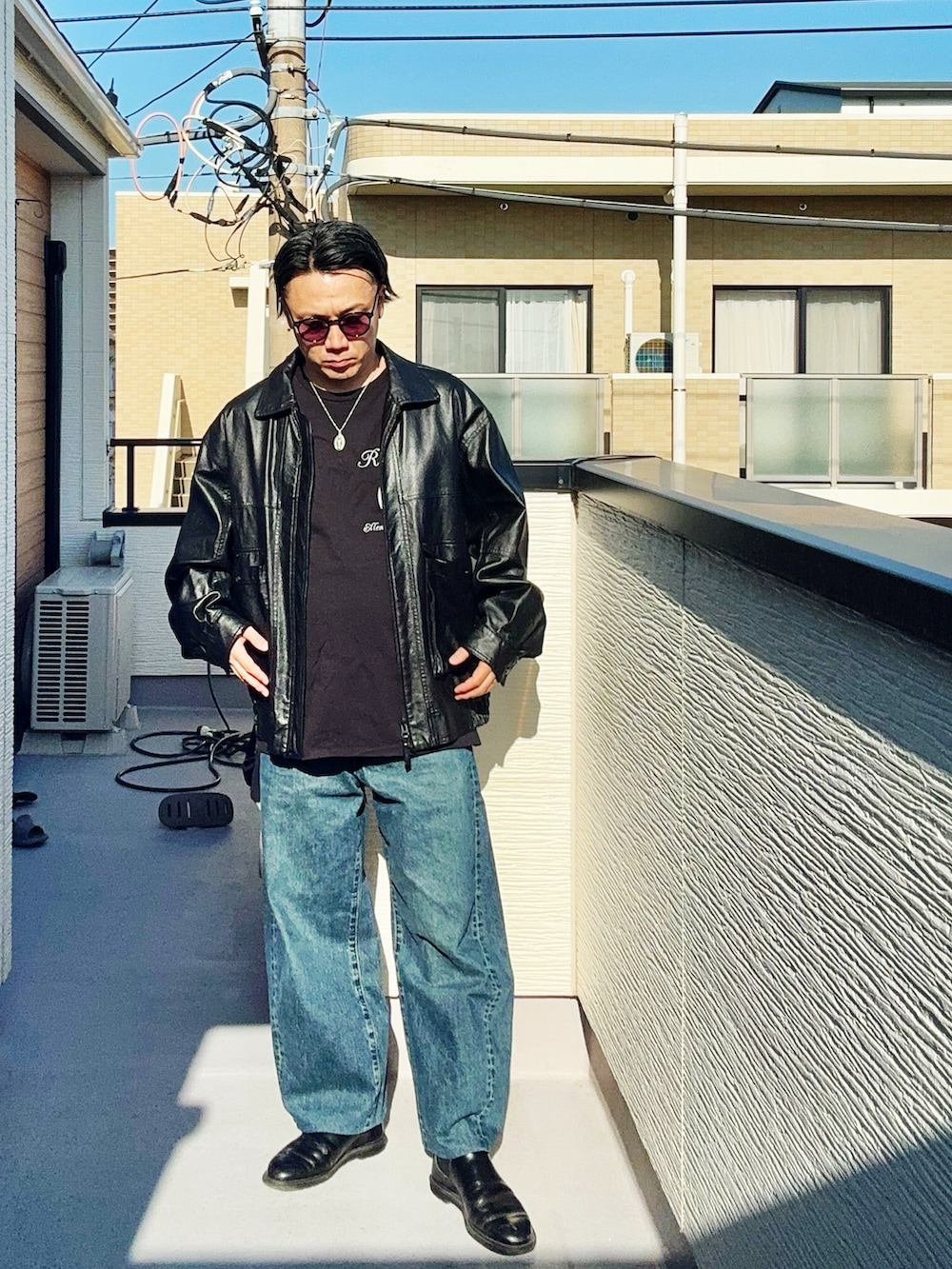 ブラック系のブルゾン、ブラック系のTシャツ/カットソー、ブルー系のデニムパンツを着用したメンズの春コーディネートの2枚目の写真