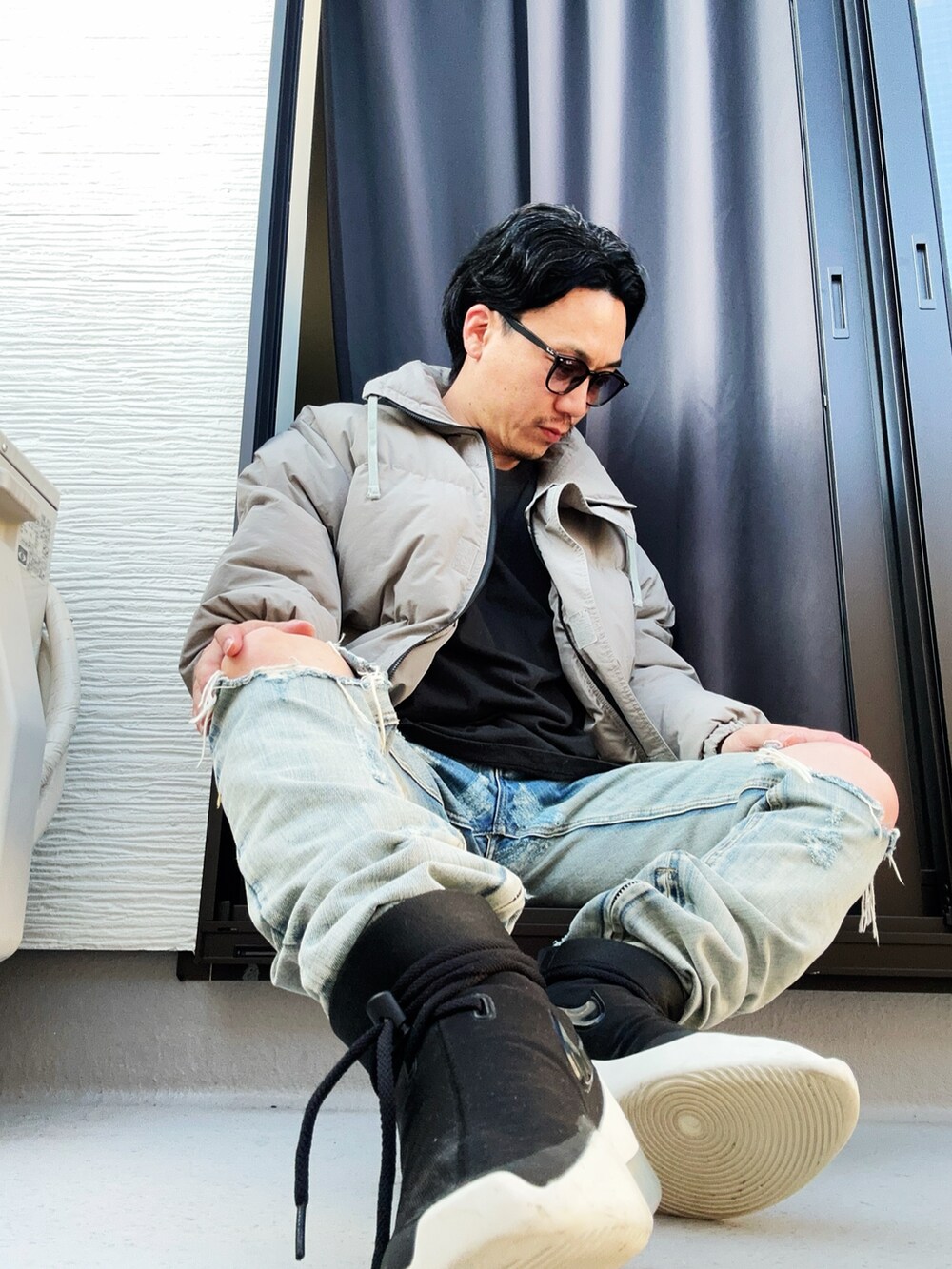 グレー系のダウンジャケット/コート、ブラック系のTシャツ/カットソー、ブルー系のデニムパンツを着用したメンズの秋コーディネートの4枚目の写真